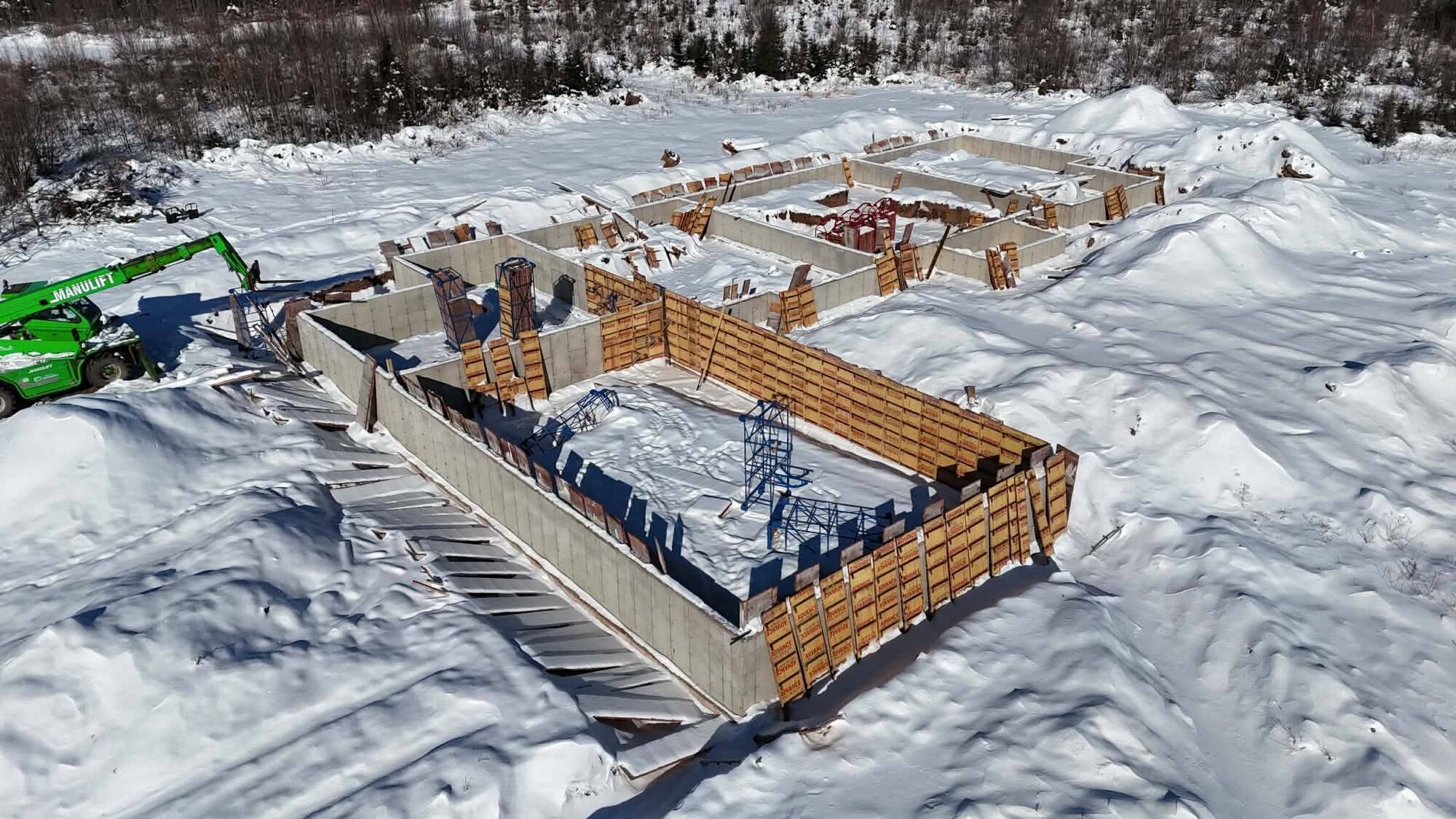 Formwork for the workshop foundation walls with snow across the site