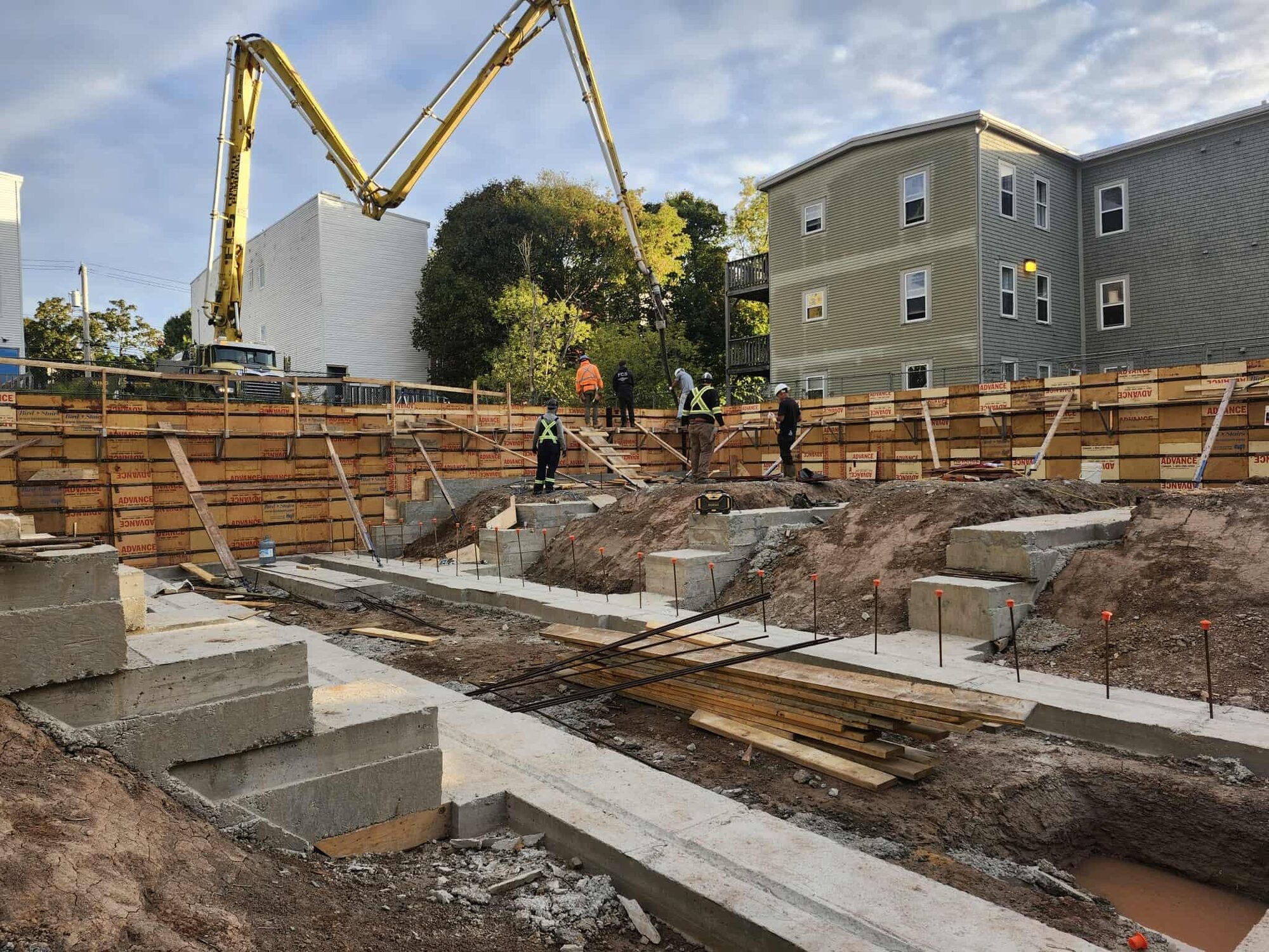 Boom pump placing concrete into formed foundation walls on a Saint John infill lot